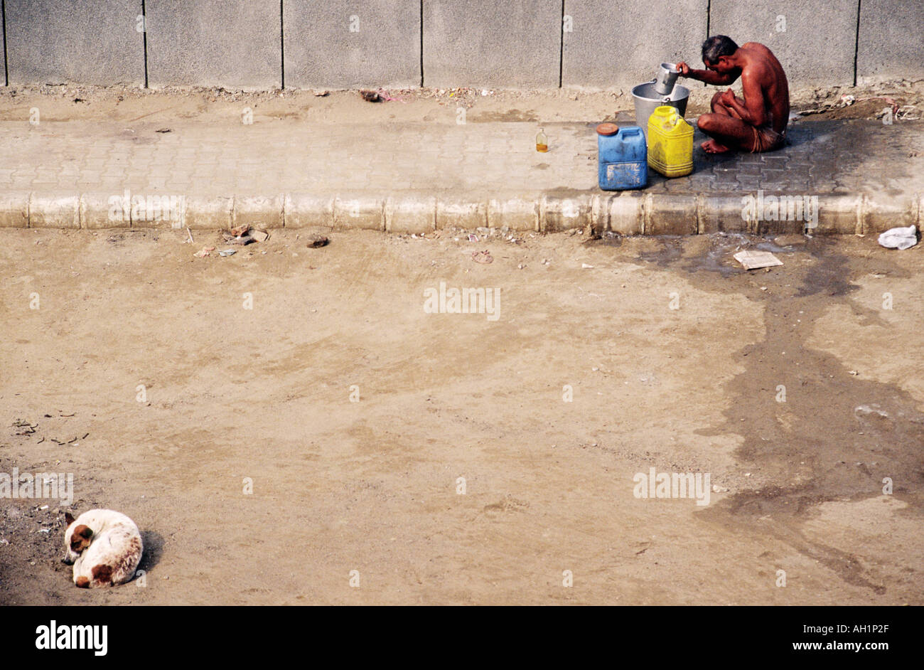Ein indischer Mann waschen sich auf der Straße in einen Eimer Hund schlafend in der Ecke Neu-Delhi Indien Asien Stockfoto