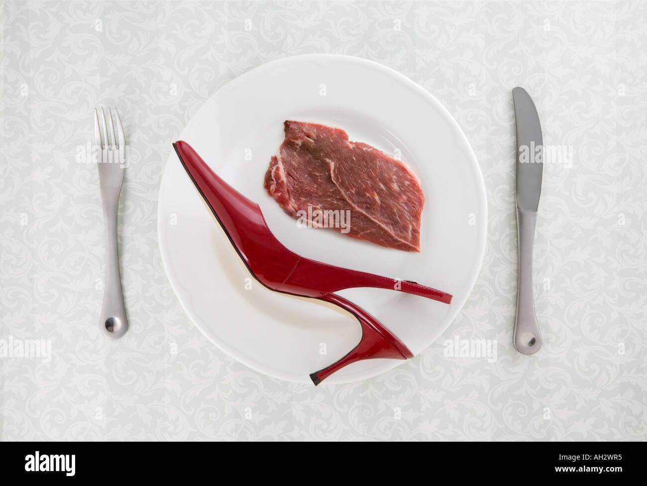 rote high-Heel mit Fleisch und Utensilien auf weißen Teller, Studio gedreht Stockfoto