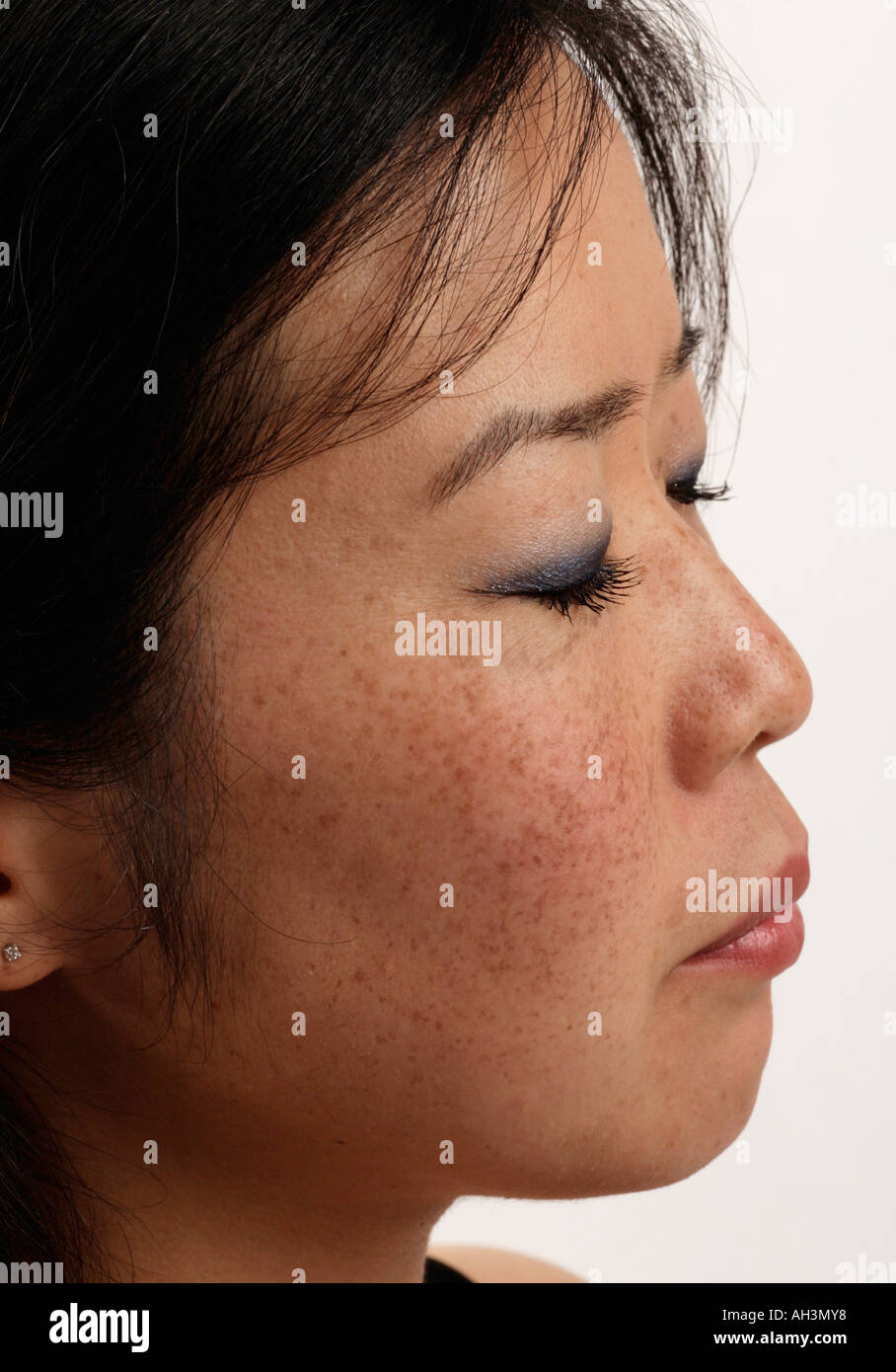 Eine junge asiatische oder japanische Frau mit Sommersprossen sie hat ihre Augen geschlossen und ruht Stockfoto