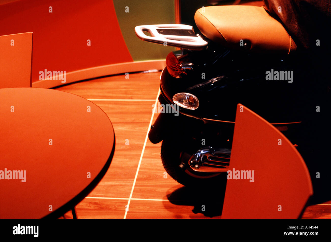 Motorroller geparkt im Innenbereich auf einem polierten Holzboden von einem Tisch und Stühlen Stockfoto