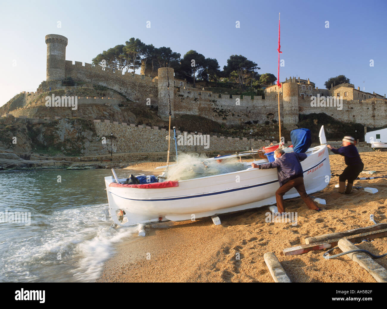 Fischer und Boot am Strand von Tossa De Mar in der Provinz Girona in Spanien bei Sonnenaufgang Stockfoto