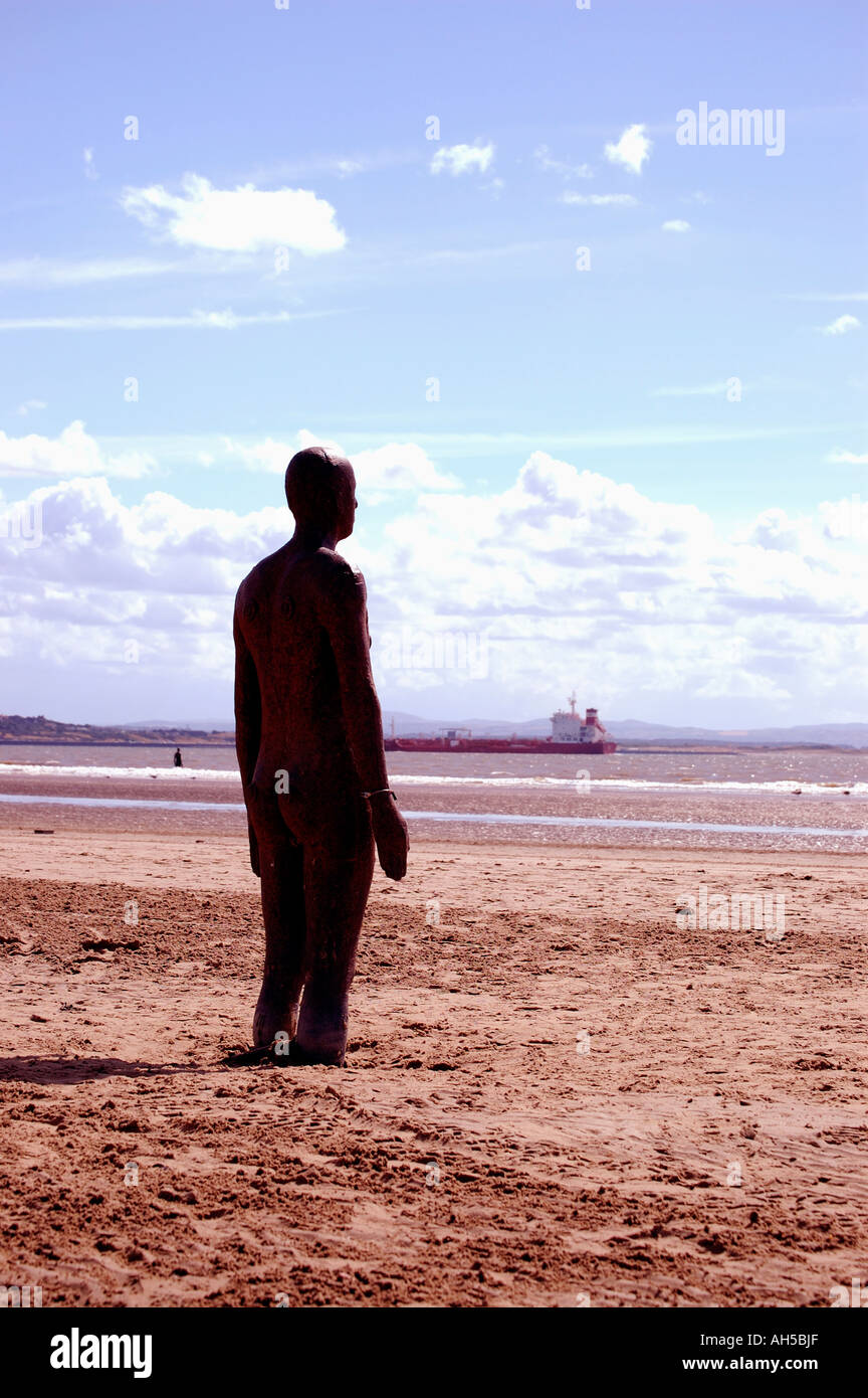 Eines der eisernen Männer Statuen von Gormleys der Ausstellung "Woanders" Blick auf das Meer am Strand Crosby, Merseyside. Stockfoto