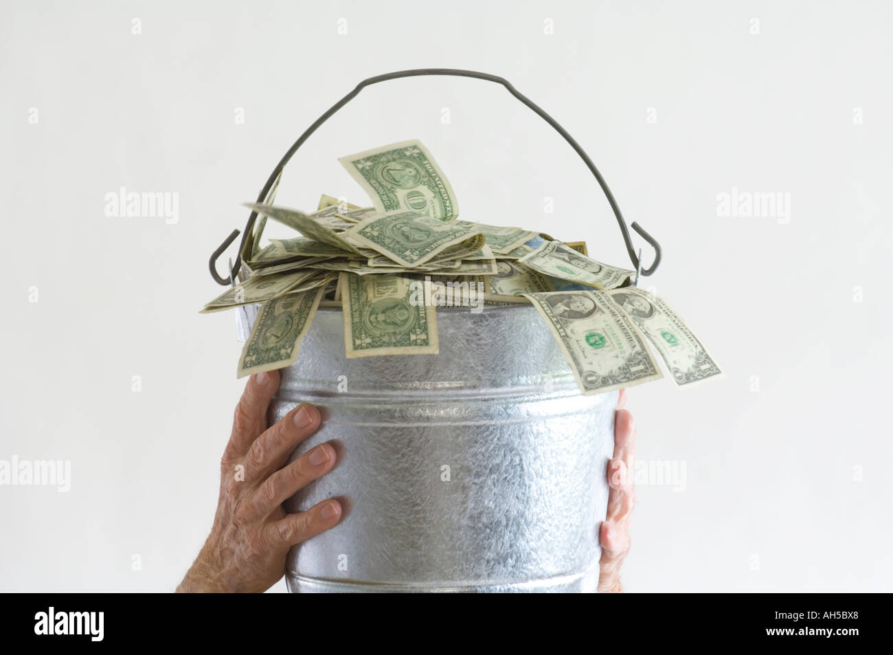 Hand, Geld aus einem Eimer von Dollarnoten Stockfoto
