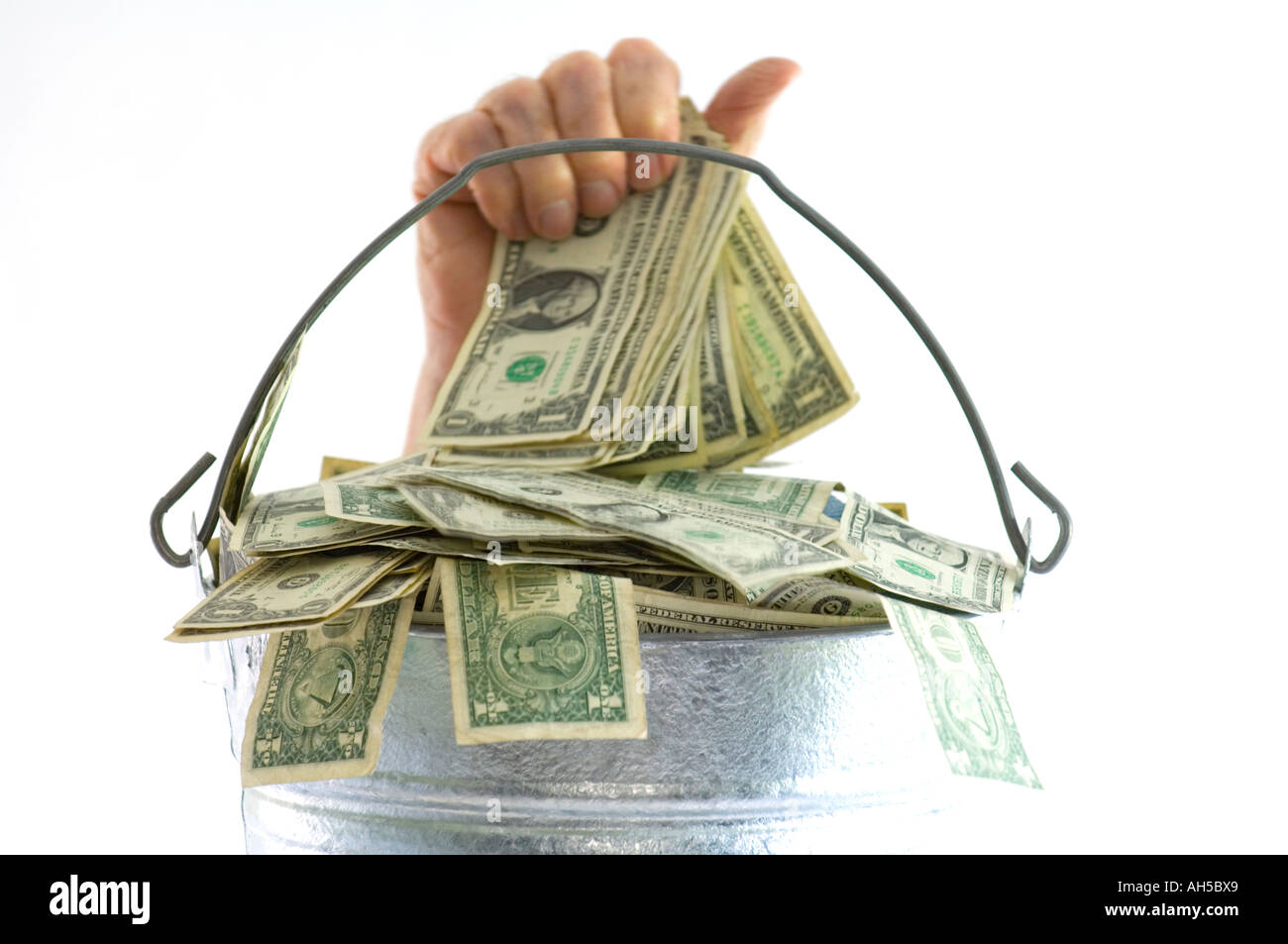 Hand, Geld aus einem Eimer von Dollarnoten Stockfoto