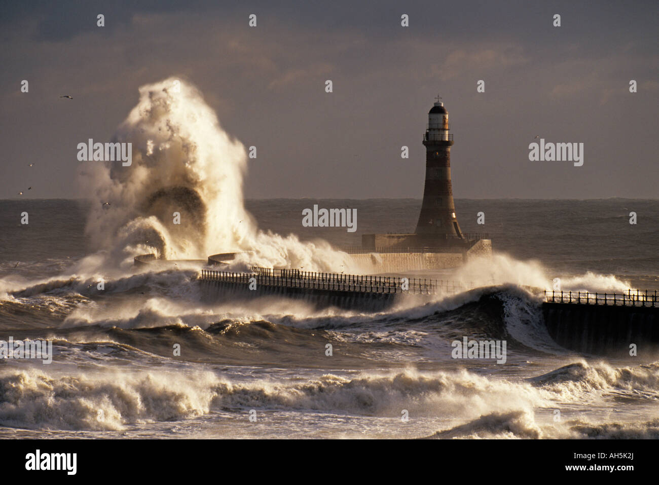 Riesige Wellen brechen über die Pier und Leuchtturm am Roker in Sunderland, Großbritannien, während ein Frühling Sturm Stockfoto