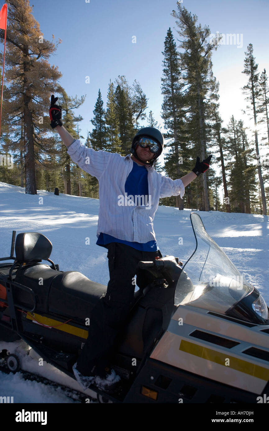 Junger Mann stehend auf einem Schneemobil Stockfoto