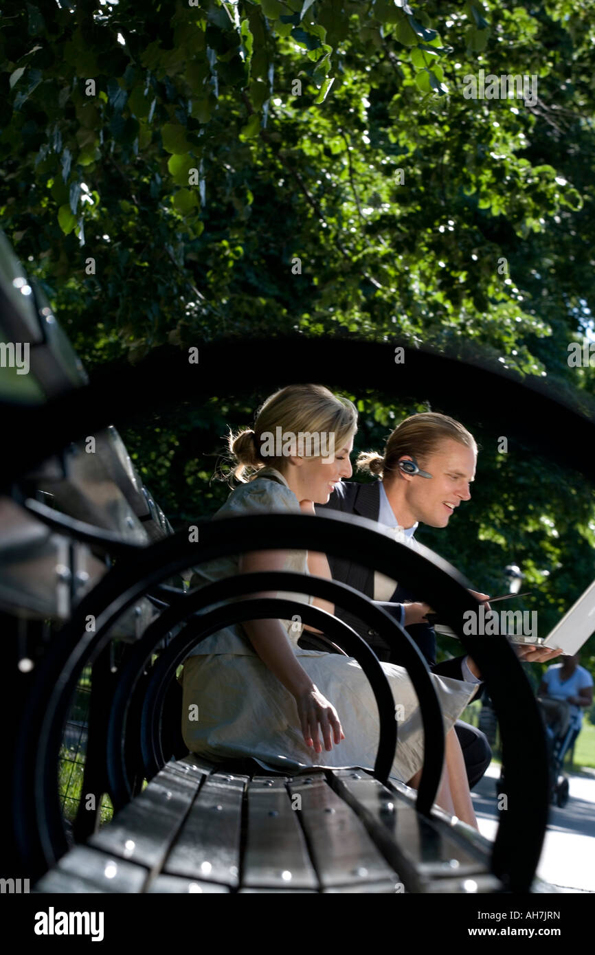 Geschäftsmann und Geschäftsfrau auf einer Parkbank sitzen und mit Blick auf einen laptop Stockfoto