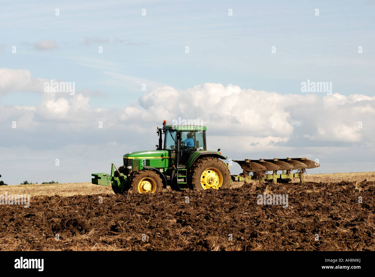 John Deere Traktor Pflügen Stoppeln Field, Warwickshire, England, UK Stockfoto