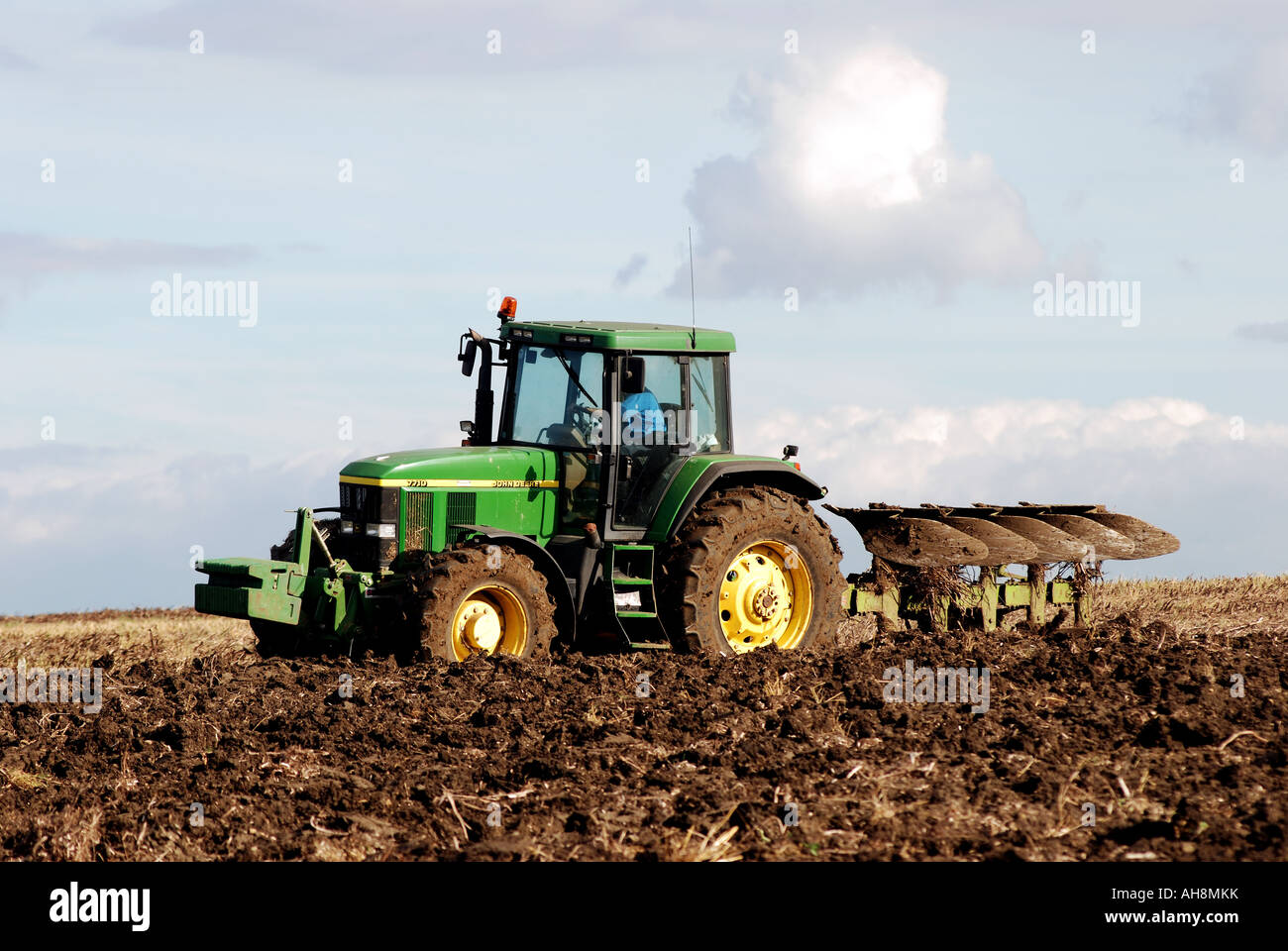 John Deere Traktor Pflügen Stoppeln Field, Warwickshire, England, UK Stockfoto