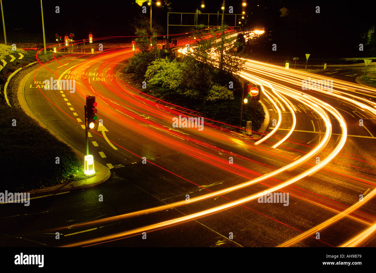 Lichtspuren des Verkehrs an einer viel befahrenen Straßenkreuzung mit Ampeln England UK Stockfoto