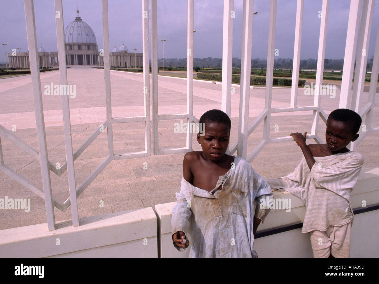 Zwei heranwachsende Jungen in zerlumpten Kleidern stehen draußen vor dem Tor der Basilika Notre Dame De La Paix in Yamoussoukro Côte d ' Ivoire Stockfoto