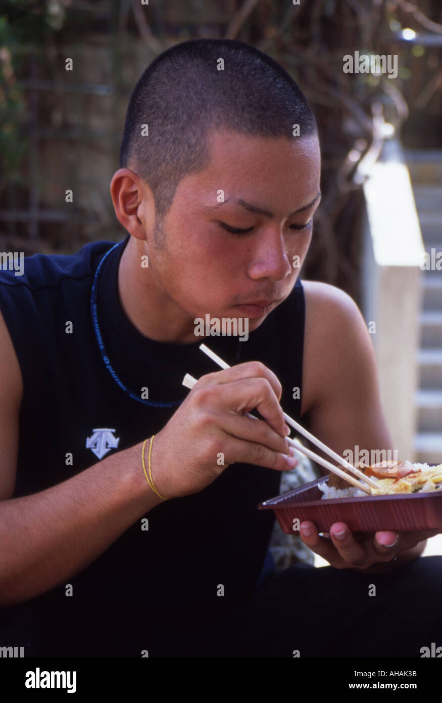 Japanische High-School junge isst sein Bento Box Mittagessen mit Stäbchen Stockfoto