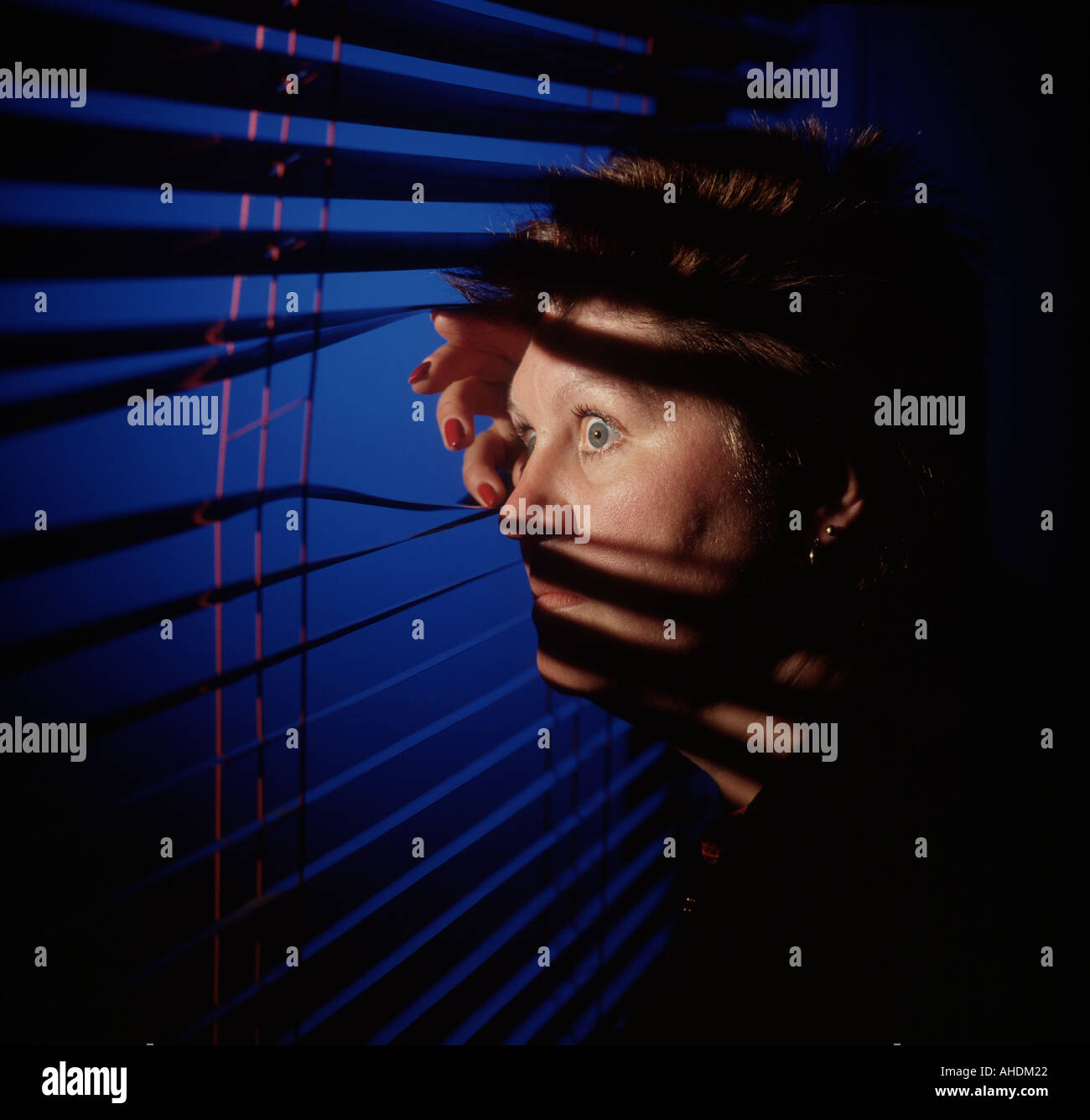 Frau auf der Suche durch Jalousien Stockfoto