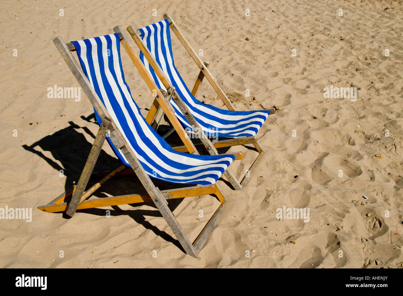 Zwei blau-weiß gestreiften Liegestühlen am Strand von Swanage, Dorset, England Stockfoto