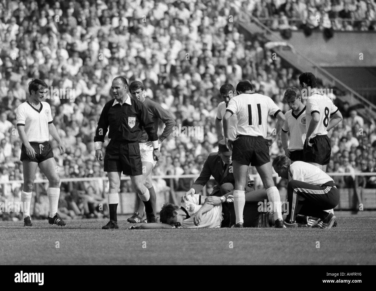 internationale Fußballspiel, 1968, Niedersachsen-Stadion in Hannover, Deutschland gegen England 1:0 verletzte Fußballspieler, v.l.n.r.: Wolfgang Overath (BRD), Schiedsrichter van Ravens aus den Niederlanden, Geoff Hurst (England), verletzte Wolfgang Weber (BRD), Max Stockfoto