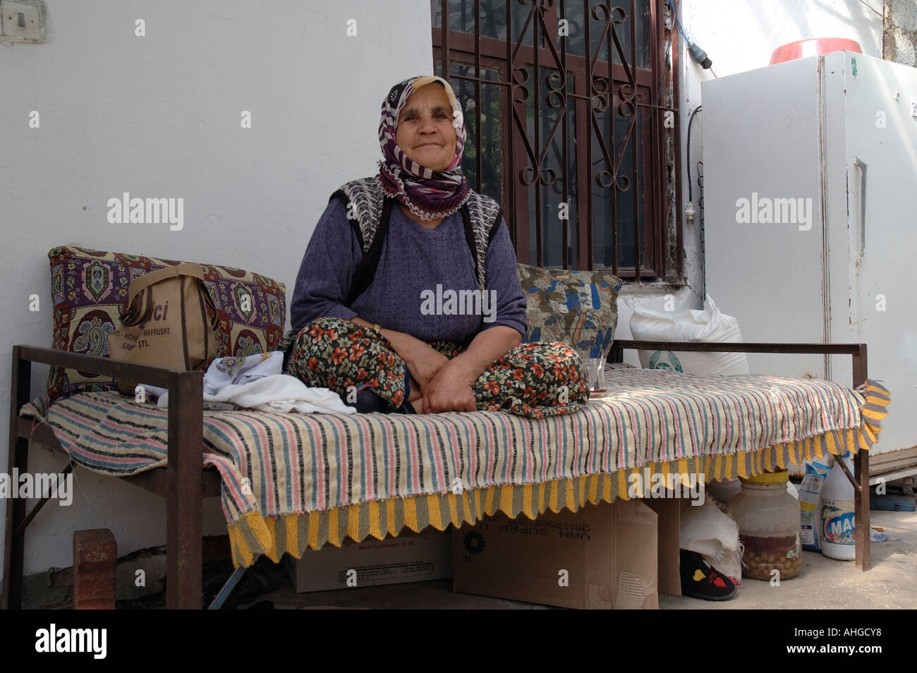 Türkische Frau sitzt auf einem Bett auf ihrer Veranda im Dorf Bezirgan in der Südtürkei Stockfoto