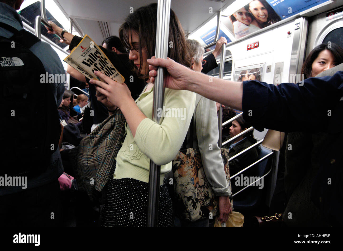 Frau liest ein Buch auf überfüllten u-Bahn, New York City, USA Stockfoto