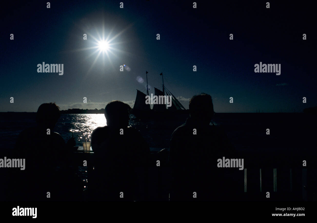 Drei Personen mit zwei meisterten Schiff hinter Silhouetten gegen Sonnenstoß und Licht vom Meer reflektiert. Key West, Florida, USA. Stockfoto