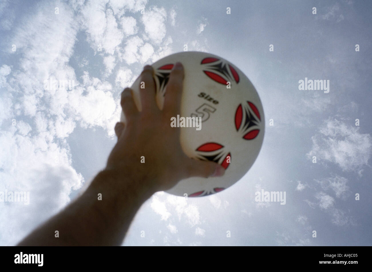 Mann Hand hält weißen Kunststoff Fußball mit roten und schwarzen Markierungen und Größe 5 mit blauen Himmel und weißen Wolken dahinter geschrieben. VEREINIGTES KÖNIGREICH. Stockfoto