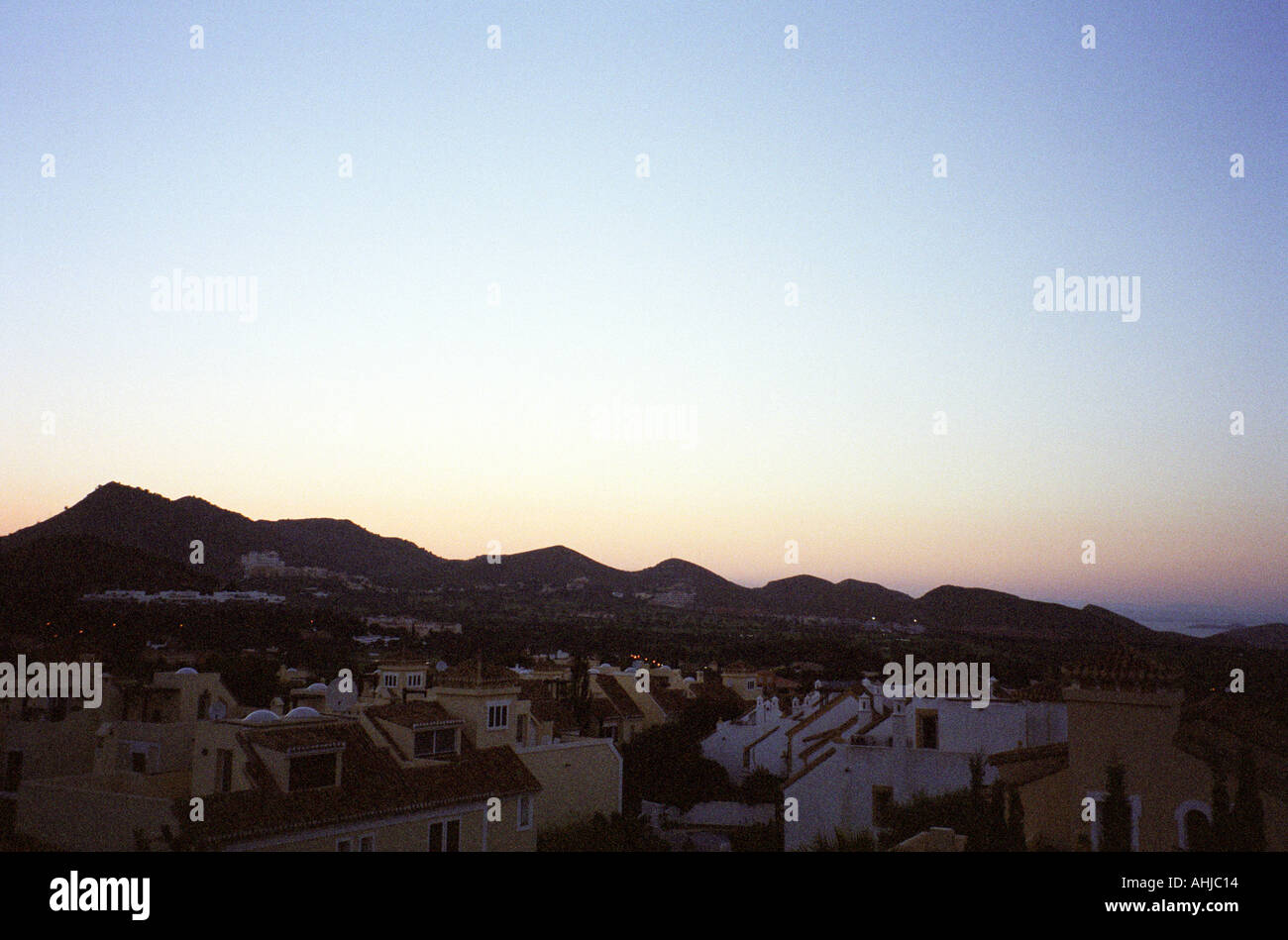 Blick über die Häuser des renommierten La Manga Resorts mit Bergen, die in der Ferne vor dem rosa Abendhimmel silhouettiert sind. La Manga, Murcia, Spanien. Stockfoto