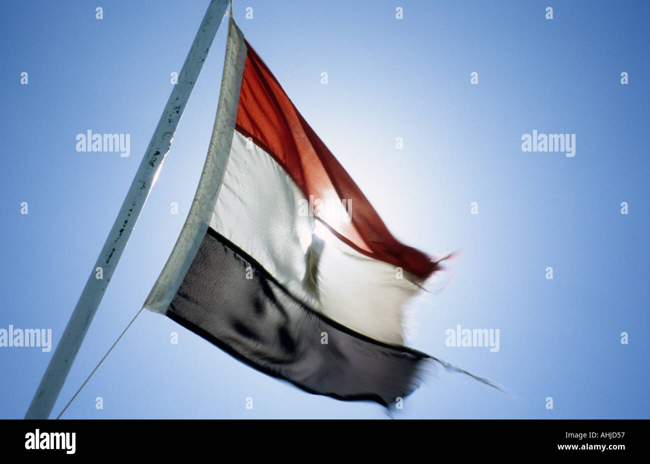 Bewegung verschwommenes Bild der zerfetzten ägyptischen Flagge im Wind mit Sonne und klaren blauen Himmel hinter. Ägypten. Stockfoto