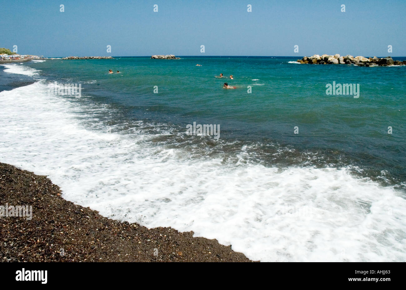 schwarze Stein sand Strand und Leute schwimmen im Ägäischen Meer Kamari Santorini Kykladen griechische Inseln Griechenland Stockfoto