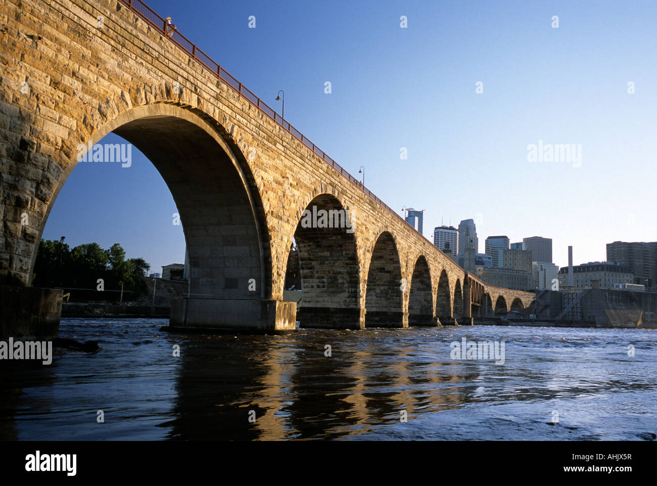 JAMES J. HILL STONE ARCH BRIDGE ÜBER DEN MISSISSIPPI RIVER. SKYLINE VON MINNEAPOLIS, MINNESOTA IM HINTERGRUND. SOMMER.  VEREINIGTE STAATEN VON AMERIKA Stockfoto