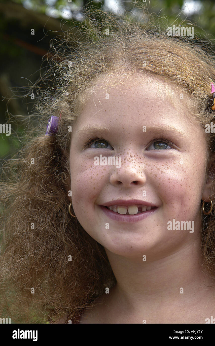 Gesicht eines lächelnden Mädchens mit lockigem Haar und Sommersprossen Stockfoto