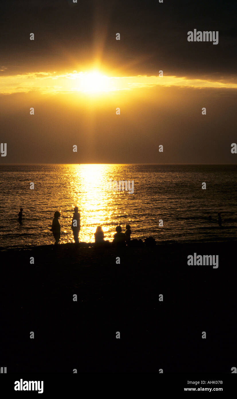 Die Menschen am St Kilda Strand silhouetted gegen goldenes Licht des Sonnenuntergangs vom Wasser reflektiert. Melbourne, Victoria, Australien. Stockfoto