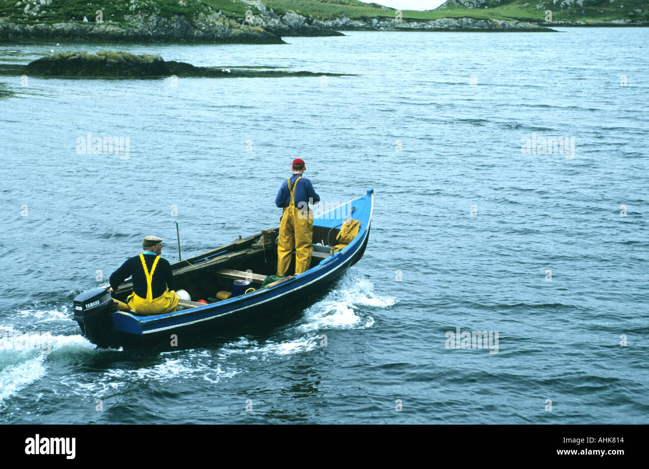 Zwei Fischer in einem traditionellen Currach ausgestattet mit einem modernen Außenbordmotor Irland auf Inishbofin, einer Insel vor Irland Stockfoto