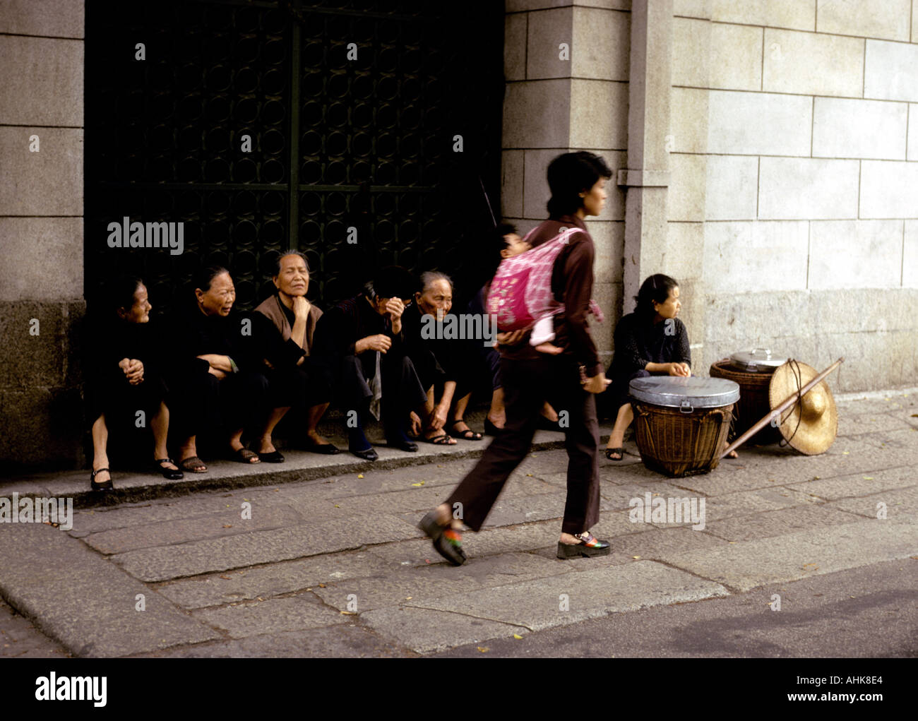 Sitzende Frauen in schwarz in einem Hauseingang beobachten das Treiben von Macao Stockfoto