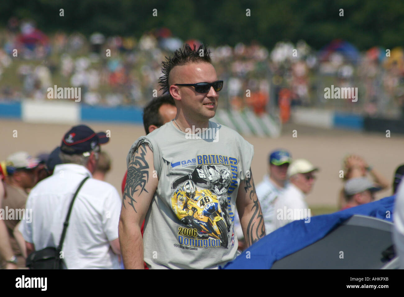 Mann bei Rennen Motorradtreffen mit Irokesenschnitt Frisur, Tattoos und Rossi Shirt. Stockfoto