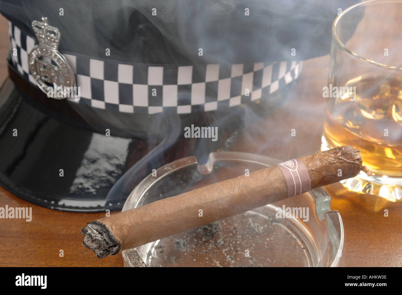 eine Polizei flache Kappe und ein Glas Whiskey mit einer kubanischen Zigarre rauchen Stockfoto