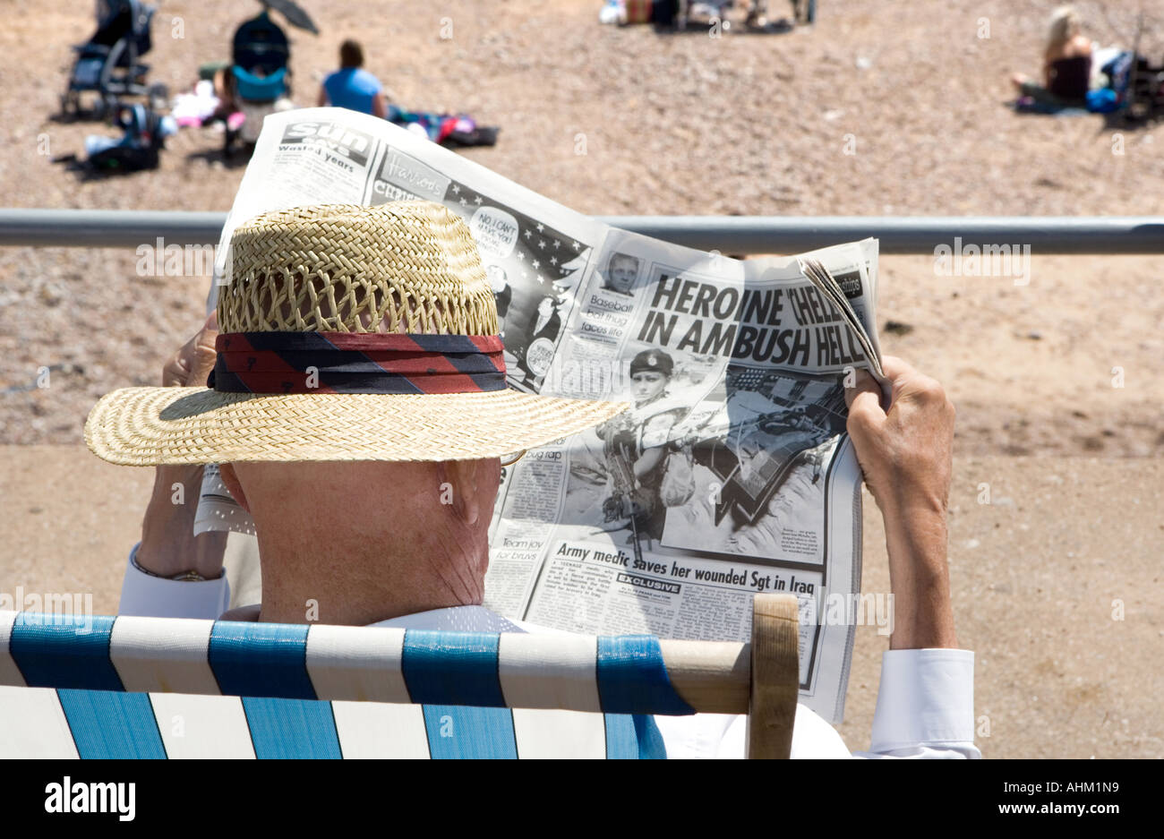 Mann im Strohhut Zeitungslektüre am Meer Sidmouth Devon England Stockfoto