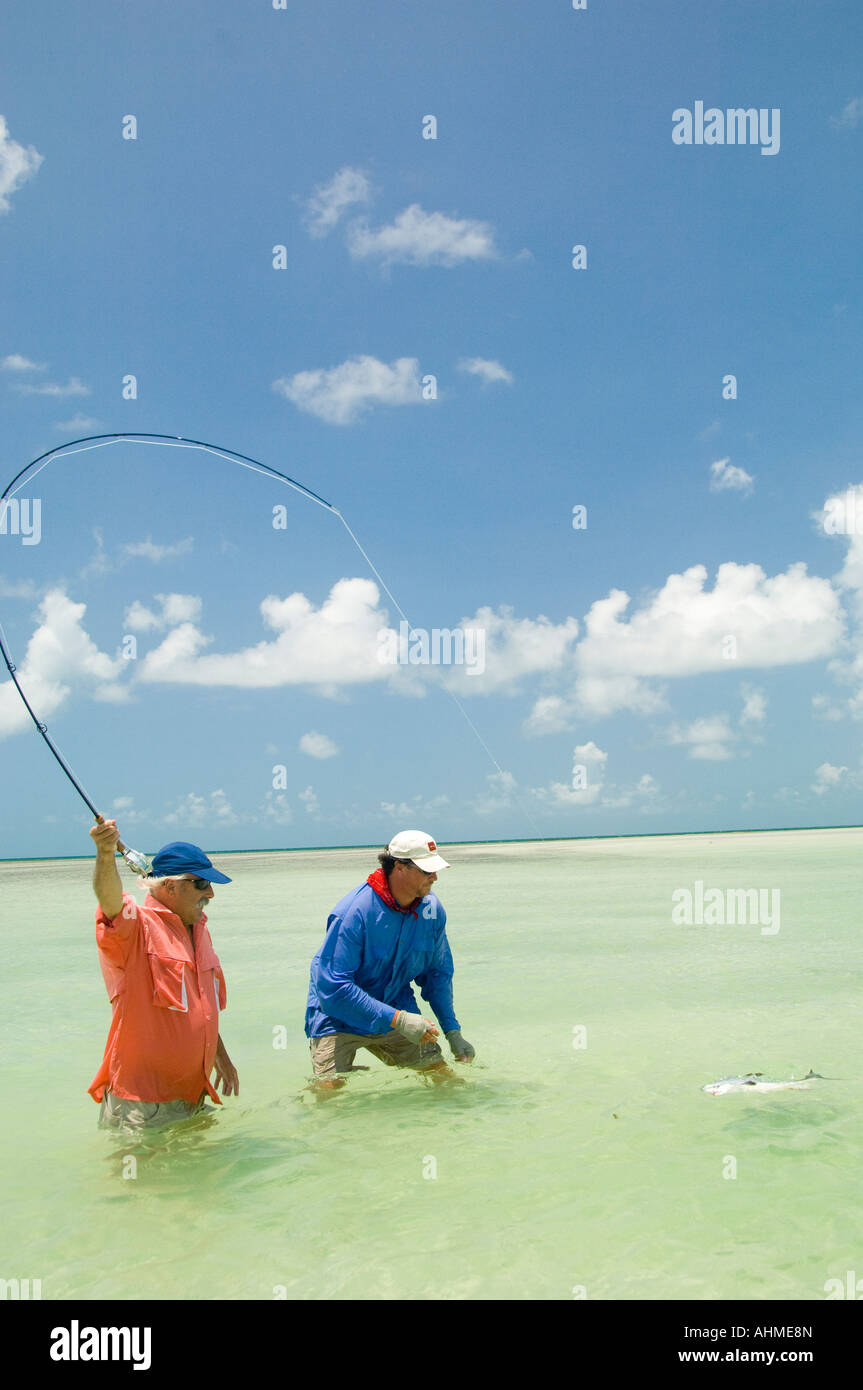 Florida Keys Fly Fisherman und Landung ein erlauben Fisch beim Fliegenfischen Guide die Wohnungen des karibischen Ozeans Stockfoto