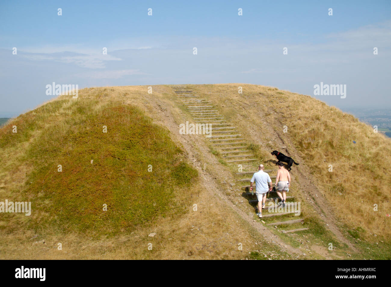 Zwei Männer und schwarze Labrador zu Fuß auf das Eisen Alter Twmbarlwm Hill Fort South East Wales UK GB EU Stockfoto
