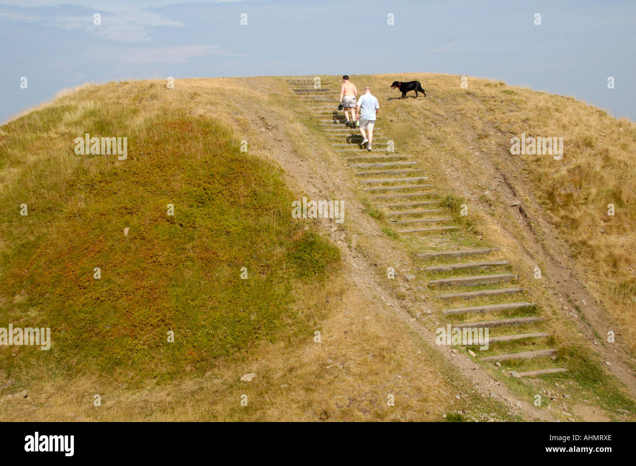 Zwei Männer und schwarze Labrador zu Fuß auf das Eisen Alter Twmbarlwm Hill Fort South East Wales UK Stockfoto