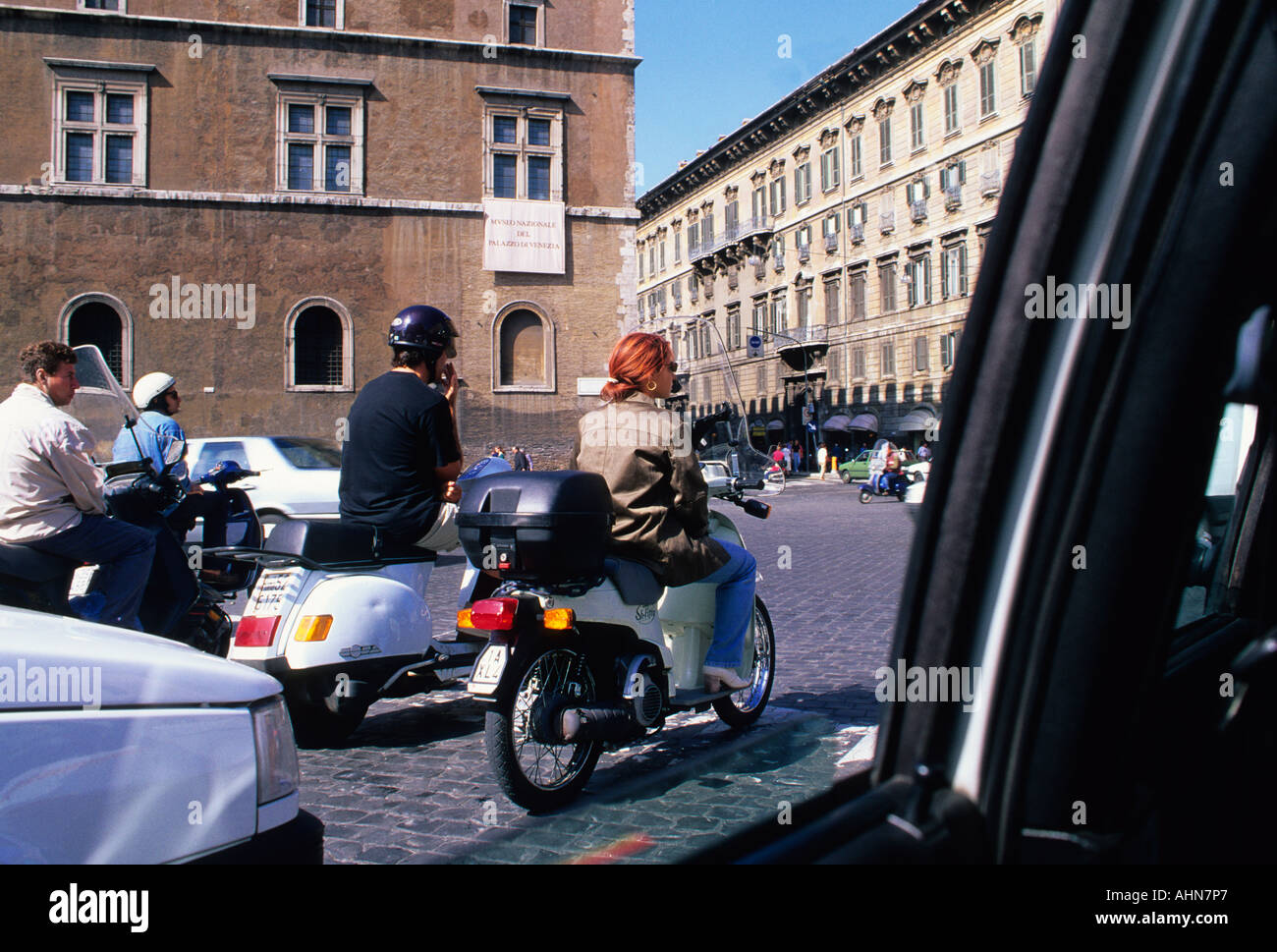 Menschen auf Motorrädern, Motorrädern, Motorrollern, Mopeds und Vespas im Mittagsverkehr vom Innenraum des Autos aus gesehen. Italienische Straßenszene. Rom, Italien Stockfoto