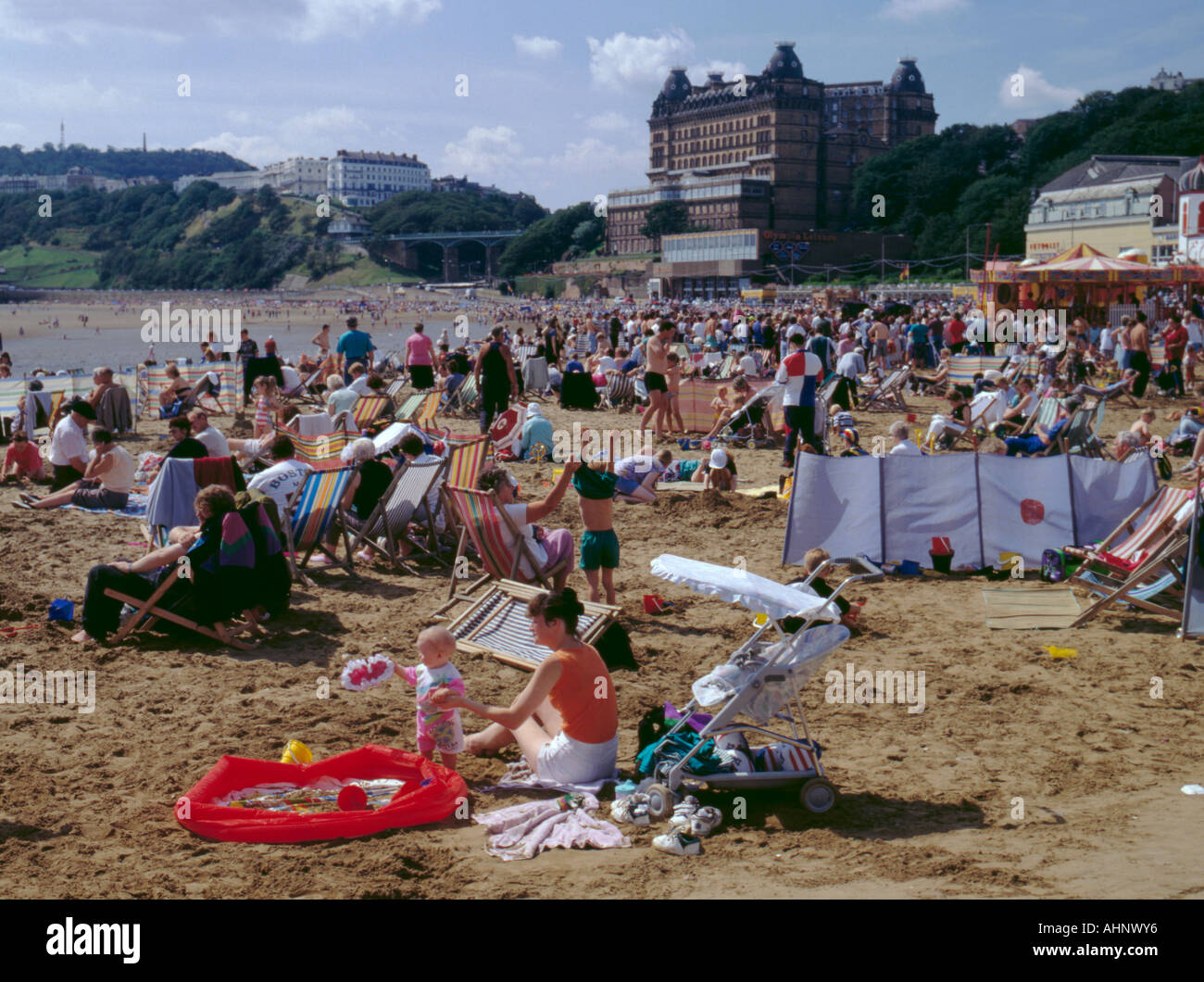 South Bay Beach überfüllt, im Sommer mit dem Grand Hotel in der Ferne, Scarborough, North Yorkshire, England, UK Stockfoto