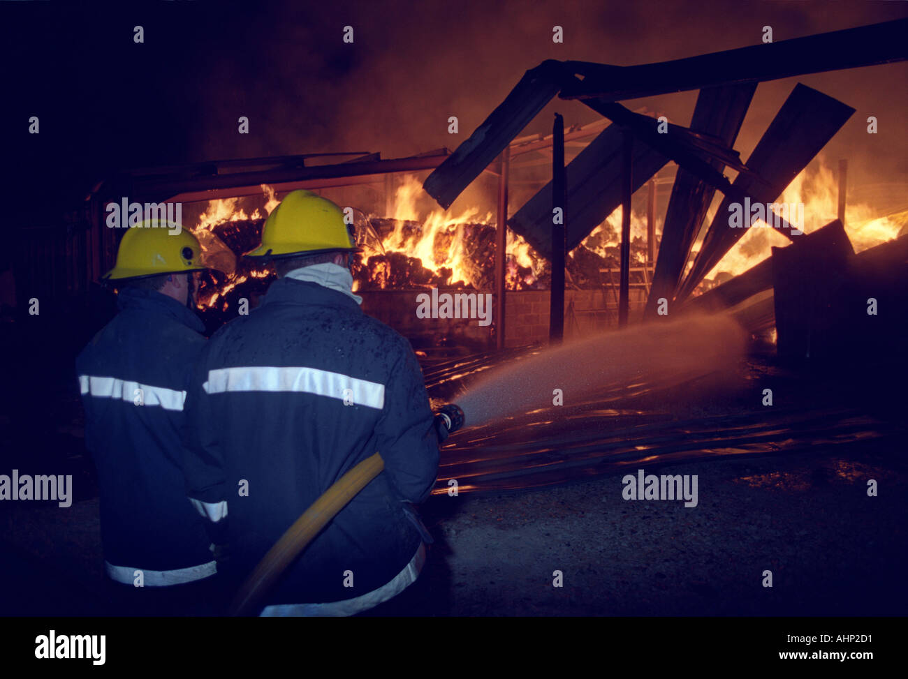 Feuerwehrleute, die mit einem Schlauch Haspel Jet eine Scheune Feuer, Großbritannien UK Stockfoto