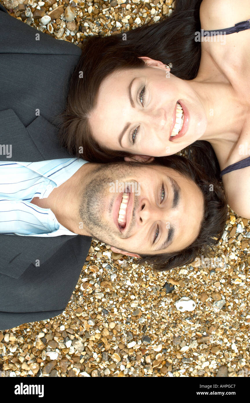 Mann und Frau liegen Kopf an Kopf auf einem Kiesstrand Stockfoto