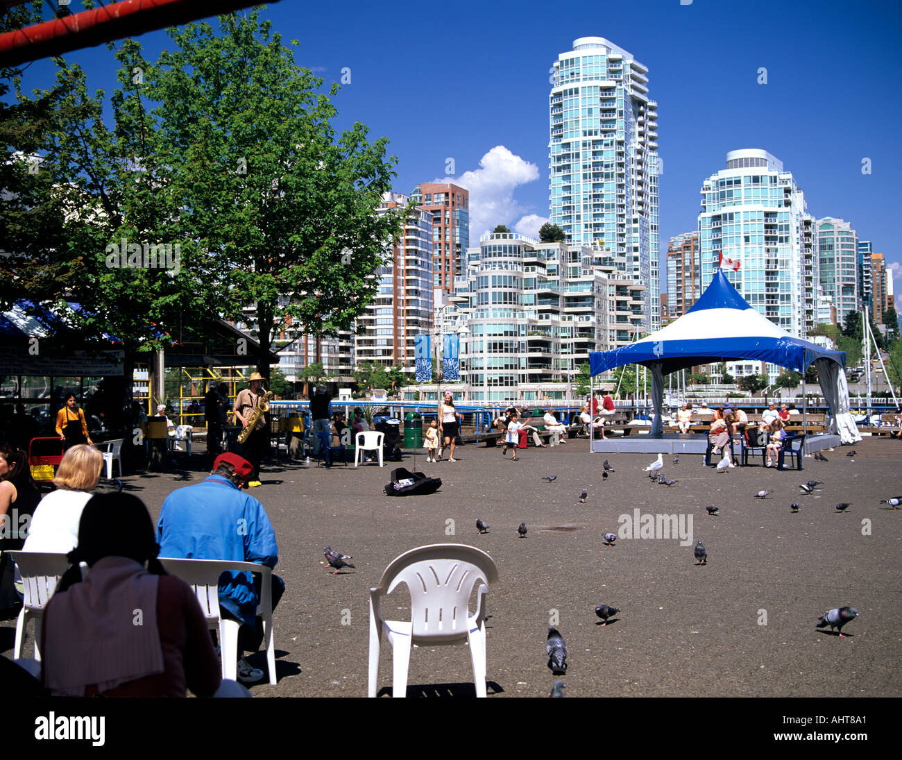 VANCOUVER BRITISH COLUMBIA Kanada kann Granville Island mit Touristen sitzen in der Sonne, die gerade einer Straße entertainer Stockfoto