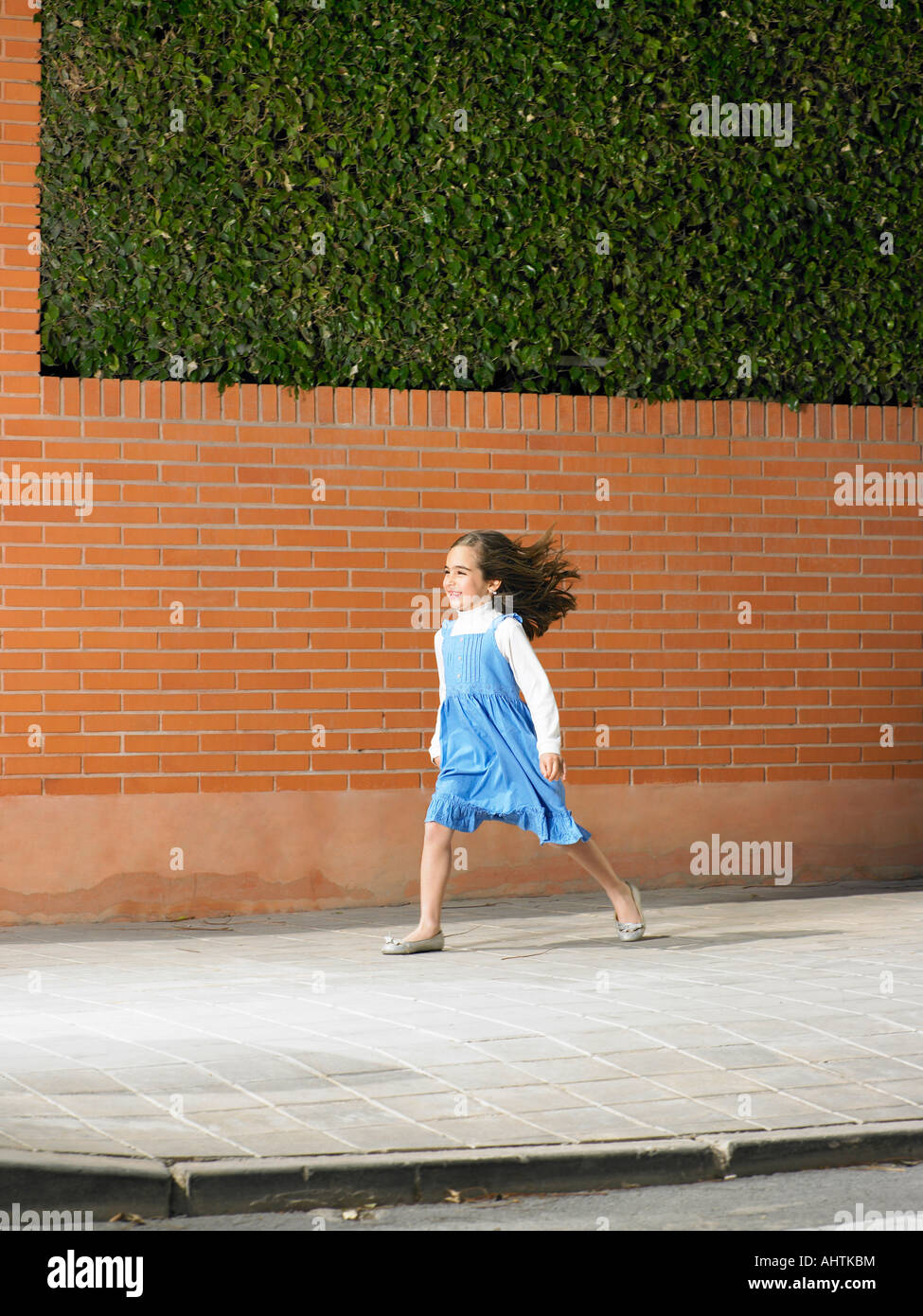 Kleines Mädchen (5-7) liefen Pflaster gegen den Wind, Alicante, Spanien, Stockfoto