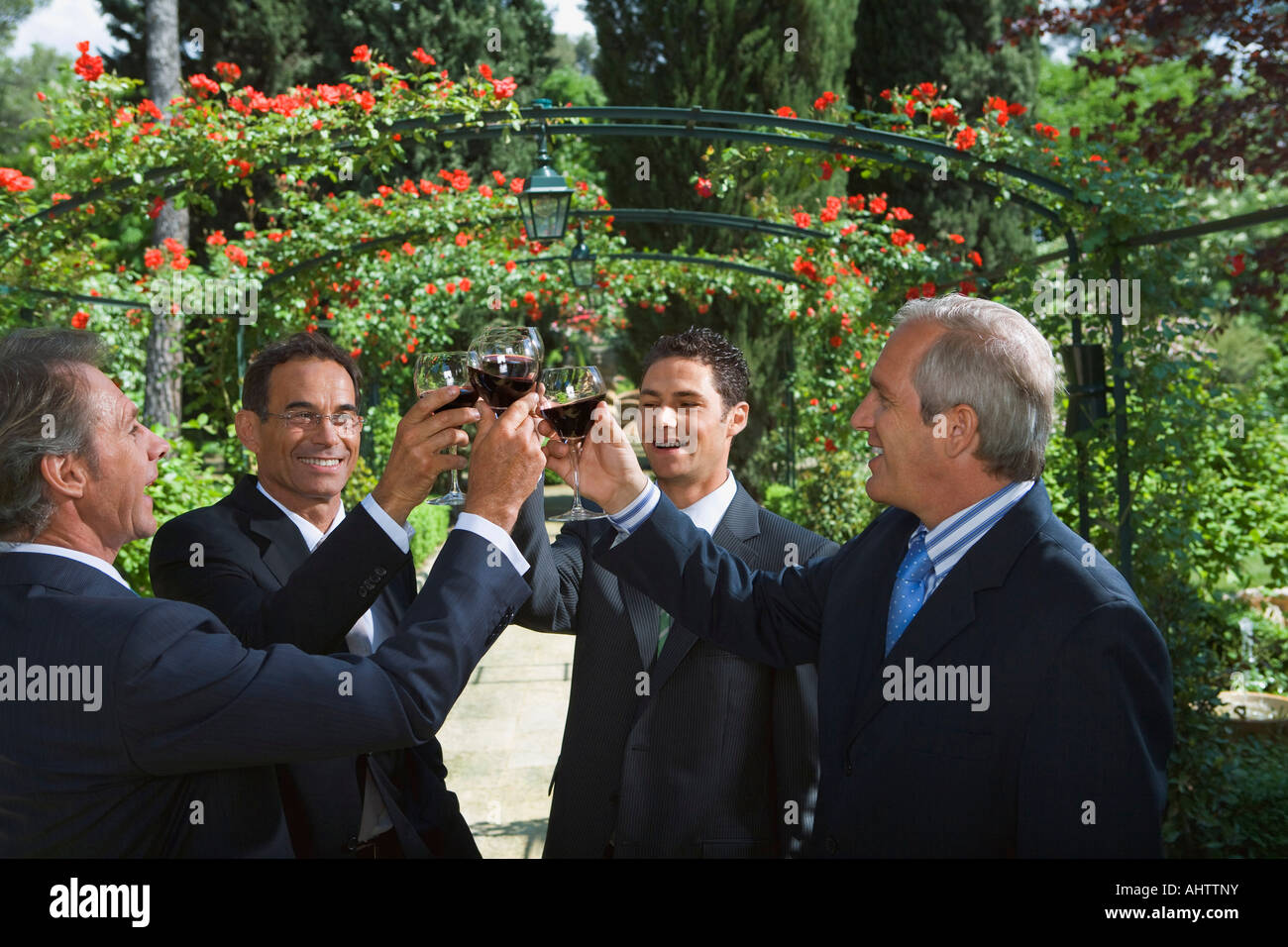 Vier Unternehmer Weintrinken in einem Garten Stockfoto