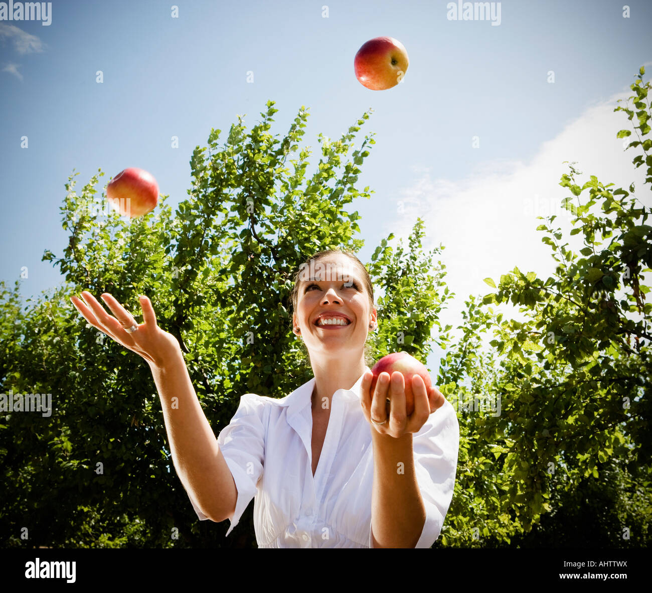 Frau jongliert Äpfel im Obstgarten. Stockfoto