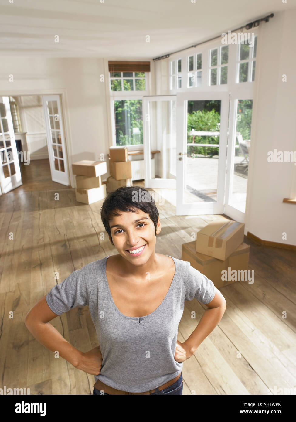 Porträt einer lächelnden Frau bewegt sich in leeren Haus. Boxen im Hintergrund. Stockfoto