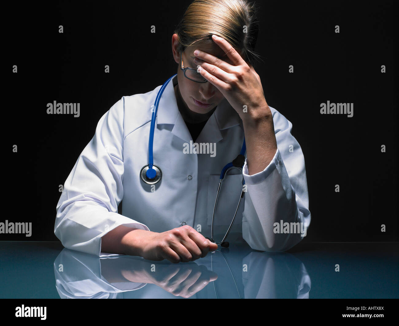 Porträt des betreffenden Ärztin an ihrem Schreibtisch arbeiten spät Kopf in der hand. Stockfoto