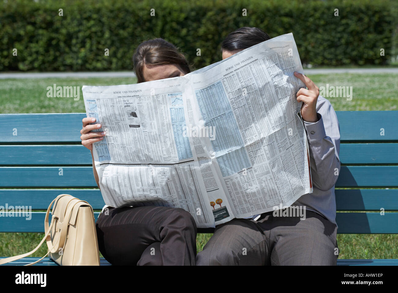 Kaufmann und Frau auf der Bank im Park zusammen versteckt sich hinter Zeitung lesen. Stockfoto
