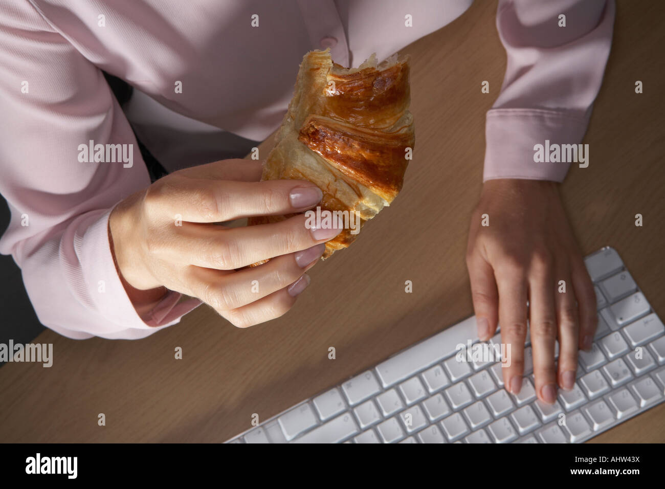 Frauenhand tippen und halten eine Croissant. Stockfoto