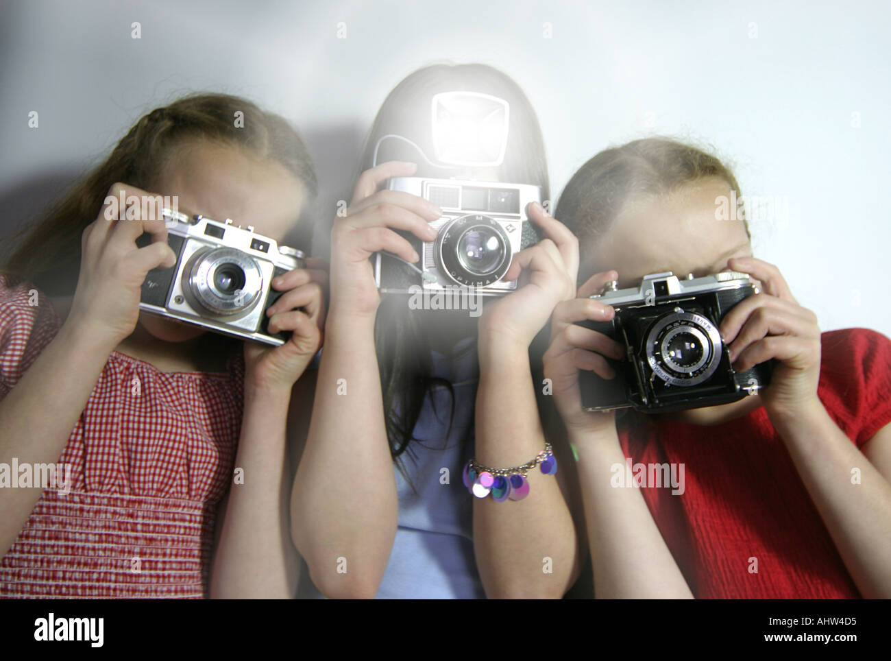Drei junge Mädchen fotografieren mit antiken Filmkameras und flash Stockfoto